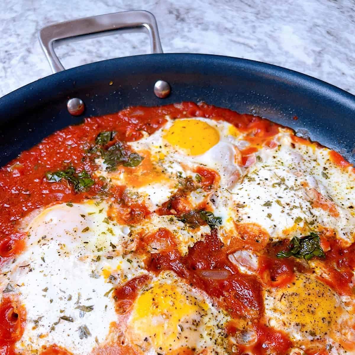 Eggs in Purgatory in frying pan with basil and ricotta