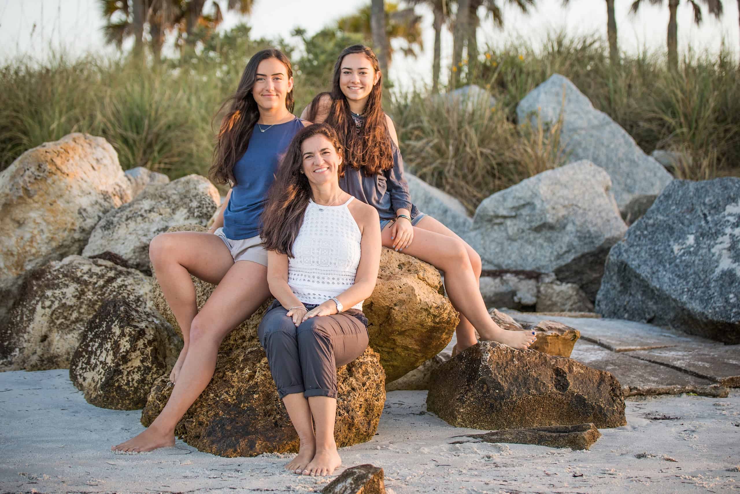 Family photo of my and both of my daughters sitting on rocks at the beach