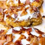 Cheesy baked chicken with crispy bacon on a sheet pan.