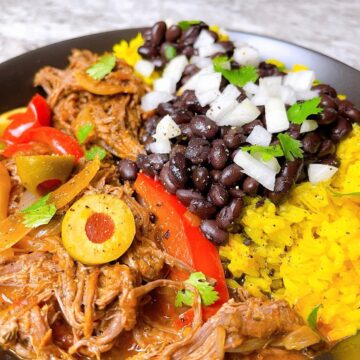a bowl of Ropa vieja with black beans yellow rice and onion
