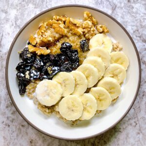 bowl of oats with bananas dried cherries walnuts and brown sugar
