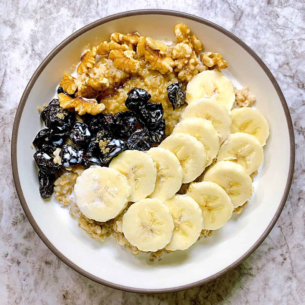 Steel Cuts Oats in bowl with banana dried cherries walnuts and brown sugar