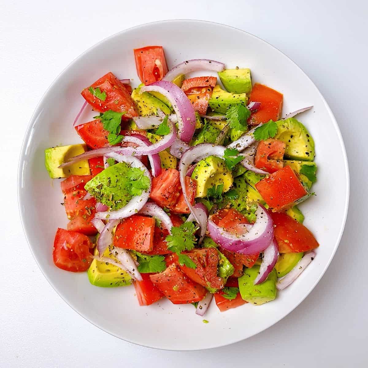 Tomato and avocado salad in a white bowl