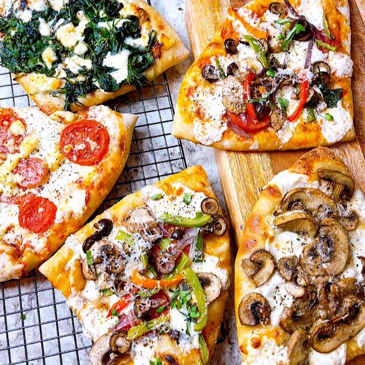 four slices of veggie pizza with different toppings on wire rack and cutting board