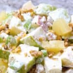 Waldorf salad in a bowl topped with walnut pieces.