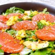 Arugula Citrus Salad with Grapefruit and Avocado in a black bowl.