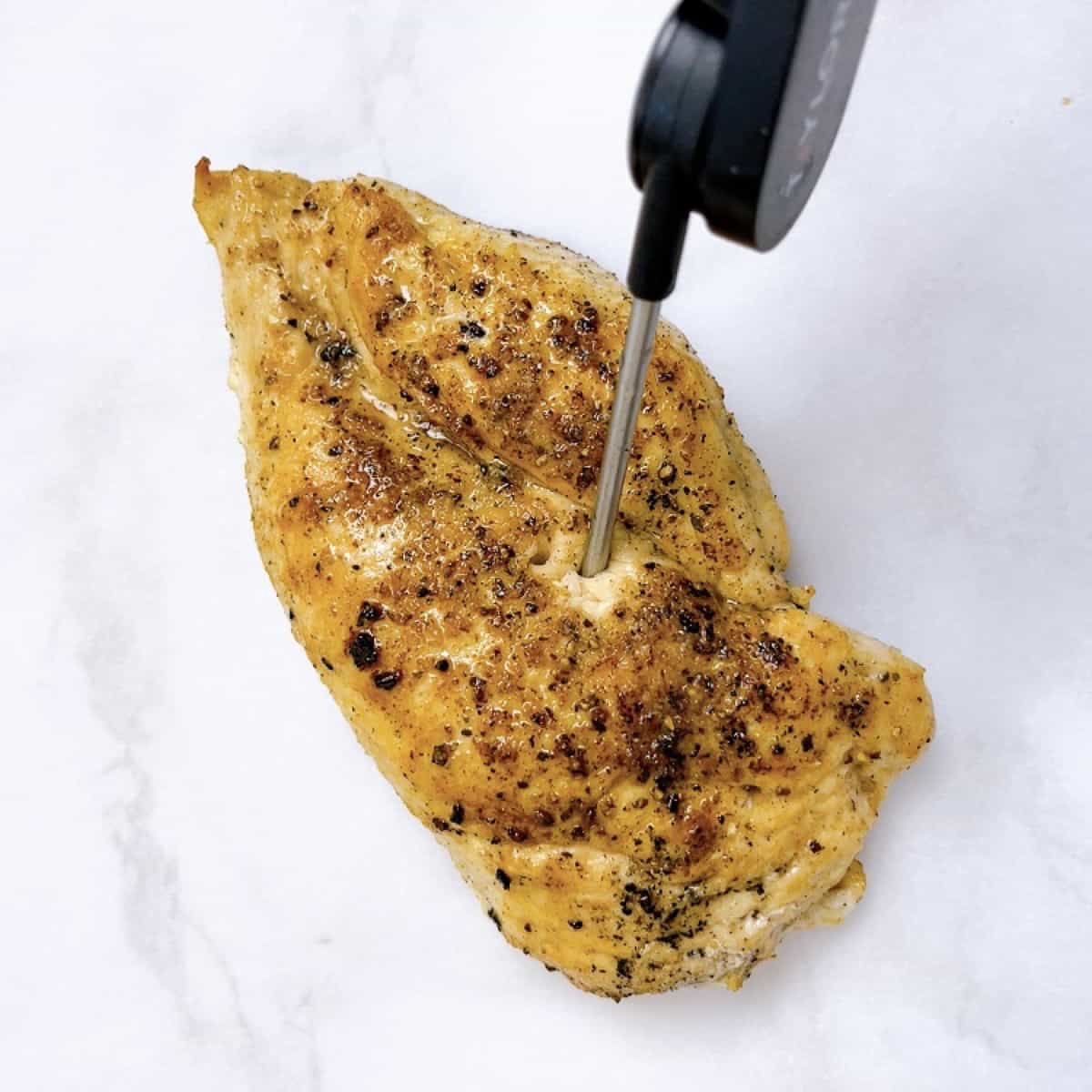 A piece of cooked chicken with meat thermometer