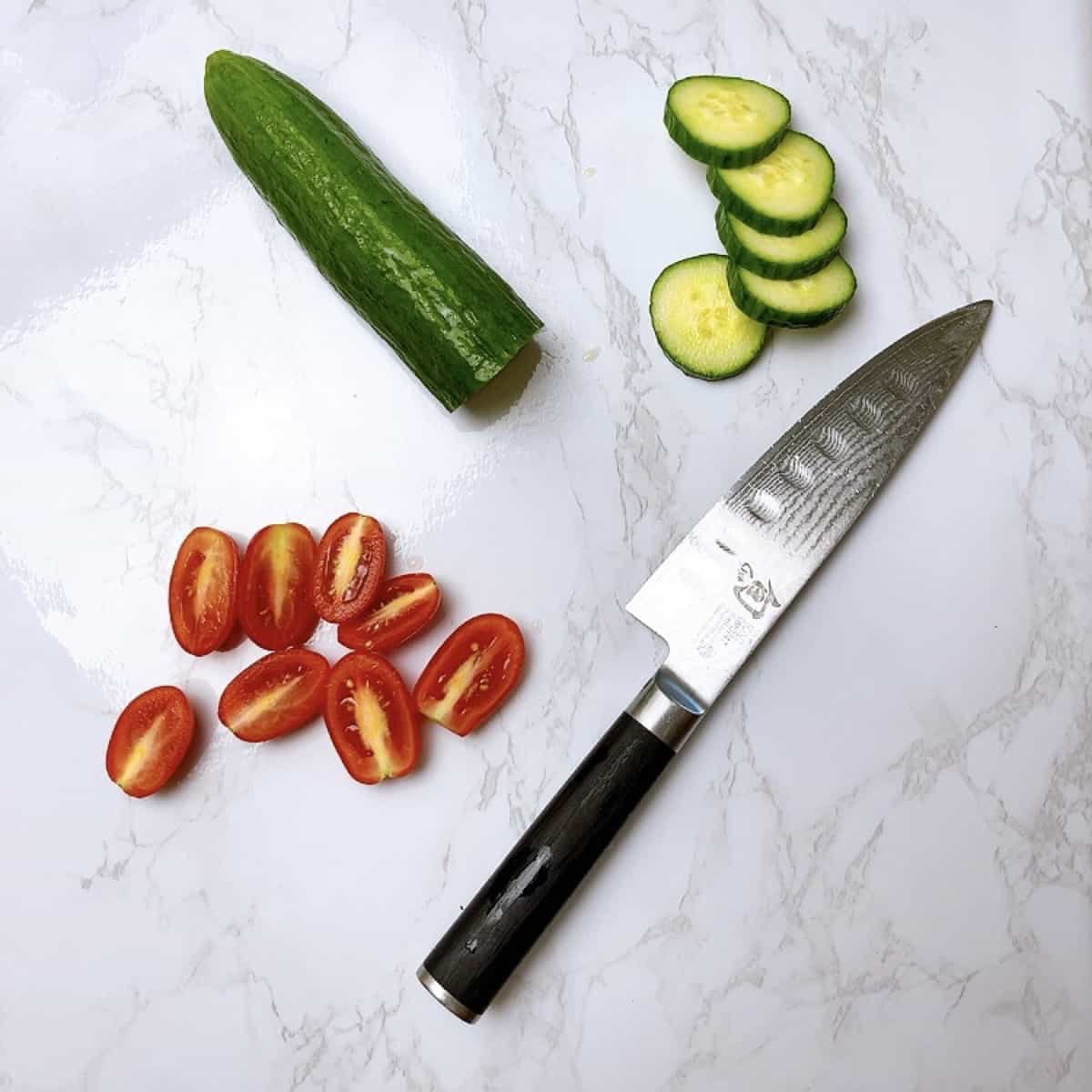 Salad ingredients chopped tomato and cucumber with knife showing