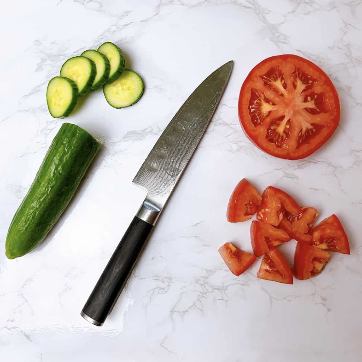 Salad ingredients tomato and cucumber chopped with knife