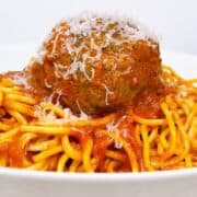 Spaghetti with meatballs on a white plate for serving.