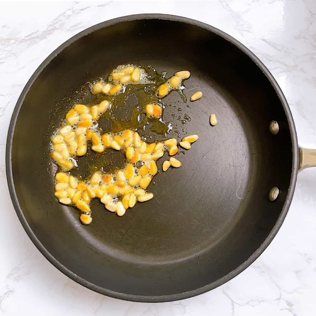Toasted pine nuts in pan with butter