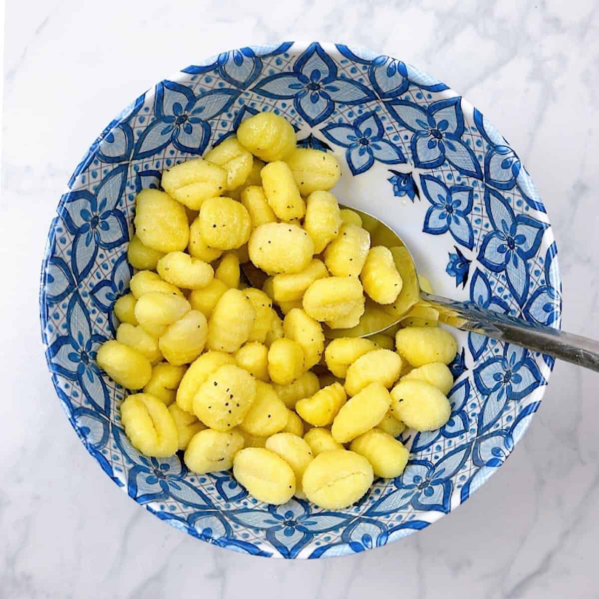 Gnocchi tossed in olive oil blue mixing bowl