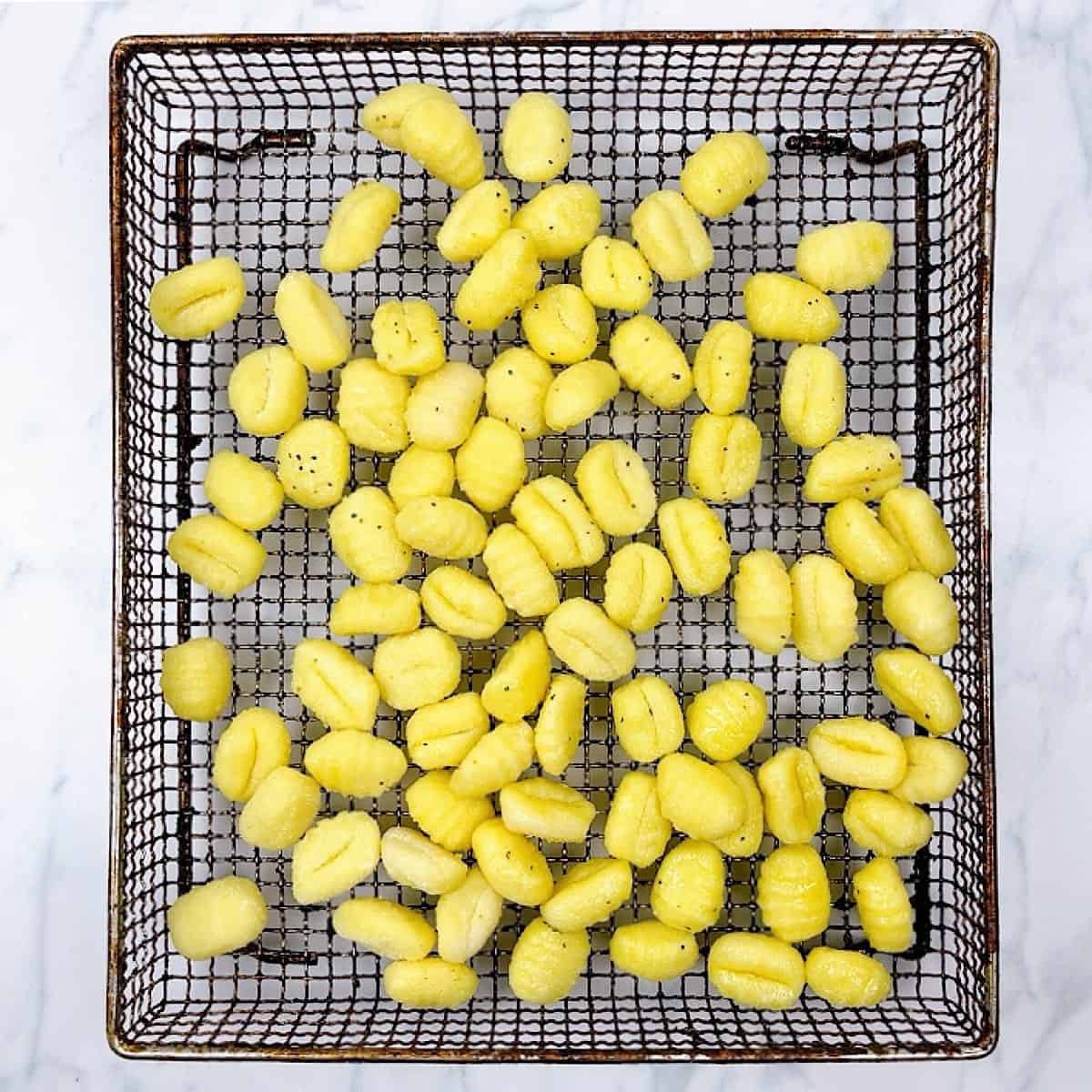 Gnocchi spread out on air fryer pan