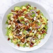 Shaved brussel sprout salad in a white bowl.