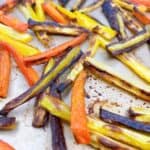 Crispy carrot fries spread out on a sheet pan.