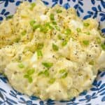 How to make a classic southern potato salad feature image close up with green onion garnish