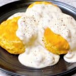 Feature image of how to make Biscuits with Southern white sausage gravy drizzled over the top.