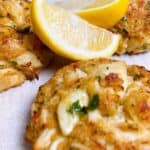 Baked crab cakes with lemon wedges resting between them.