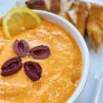 Easy tirokafteri recipe greek spicy feta dip feature image close up with lemon and kalamata olives on platter with warm pita