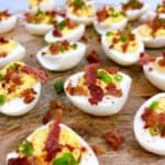 Best southern deviled eggs recipe with crispy bacon feature elegant close up on wooden board with all the toppings