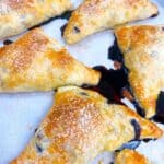 Blueberry turnovers with puff pastry feature image close up with blueberry syrup oozing out
