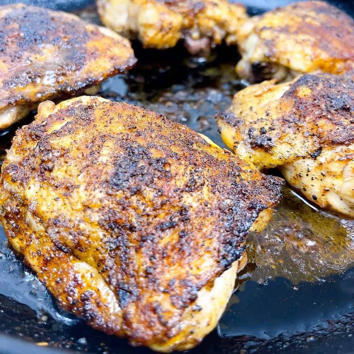 Cast Iron Chicken Thighs close up in skillet with crispy crust feature image