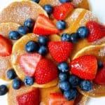 Easy mini pancakes for 4th of July recipe feature image. on platter with berries powdered sugar and syrup.