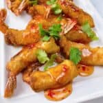 Thai shrimp in a blanket with sweet chili sauce and cilantro on a platter.