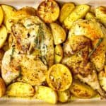 Greek lemon chicken nestled with potatoes and a thyme garnish.