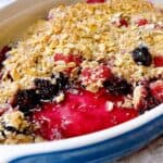Triple berry crisp with a scoop out of the dish to show berry center and oat topping.