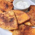 Easy air fryer cinnamon pita chips recipe feature image close up of pita triangles with whipped cream cheese.