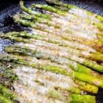 Cooked asparagus with cheese and panko in cast iron skillet.