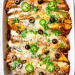Baked chicken tinga enchiladas in casserole dish with all the toppings.