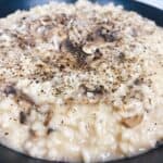 Creamy mushroom risotto with truffle oil easy Italian recipe feature image close up in black bowl