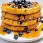 Blueberry waffle recipe feature image close up stacked with syrup dripping and blueberry topping
