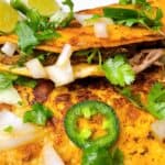 easy crockpot birria tacos hero image close up of two tacos with toppings.