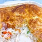 southern chicken pot pie with puff pastry feature image. close up in casserole dish cooked with inside showing scooped.