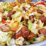 easy southern fried cabbage with sausage and bacon feature image close up in skillet
