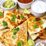 Easy vegetarian quesadillas with black beans and corn sliced up with toppings on a platter.