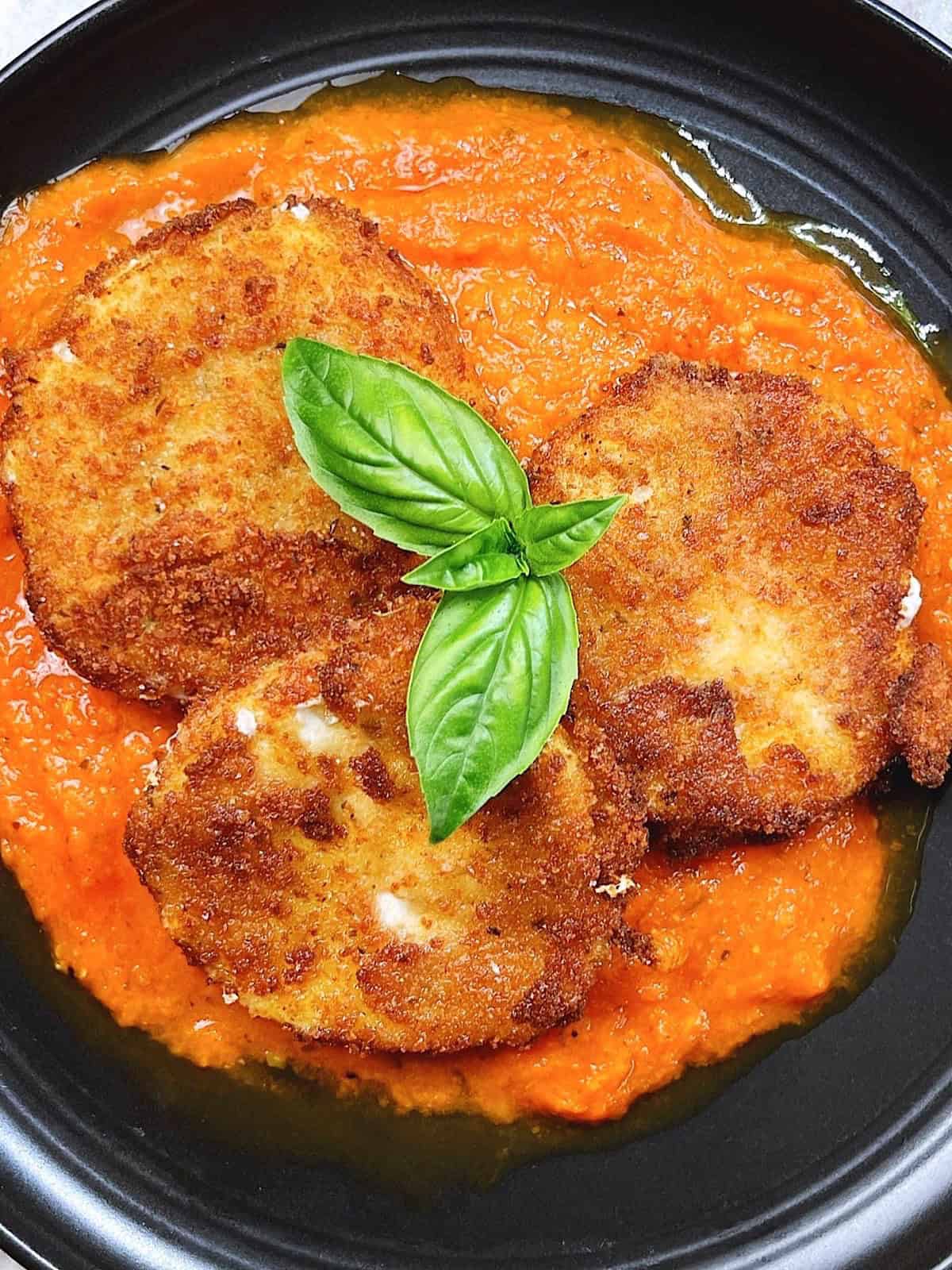Easy Italian fried cheese recipe with fresh mozzarella and marinara hero image. close up on plate with basil leaves on top