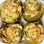 Four Italian stuffed artichokes in a casserole dish.
