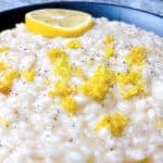 Lemon risotto recipe with parmesan and white wine feature image close up with zest in black bowl