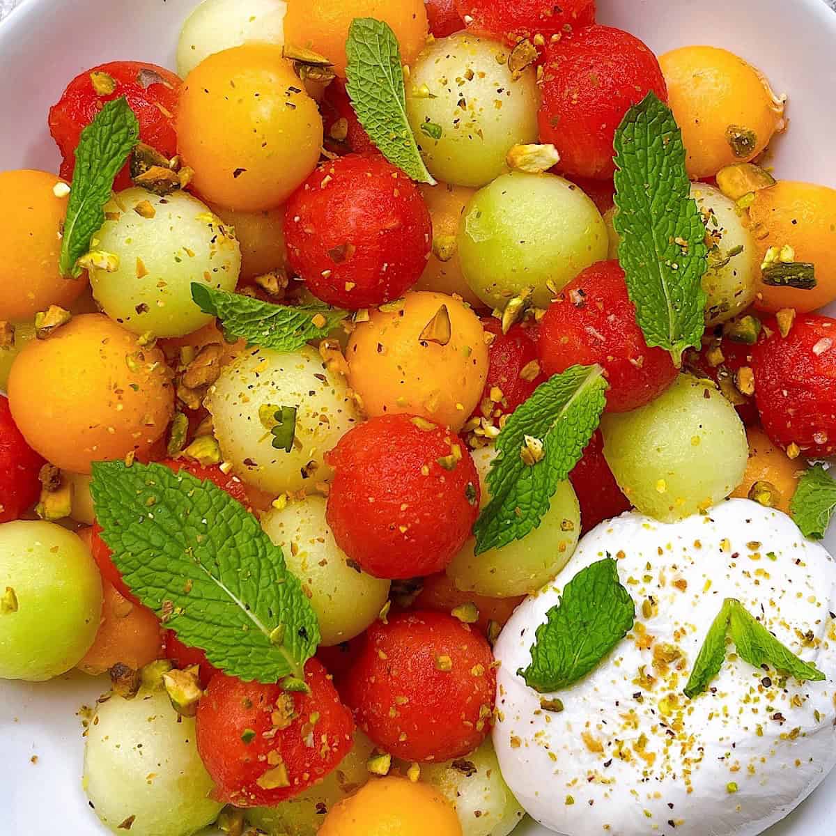 Melon salad with burrata pistachio top down image close up dressed with toppings