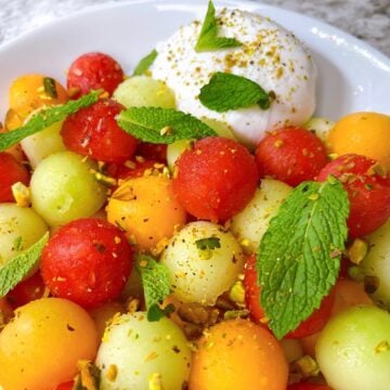Melon salad with burrata pistachio and mint feature image close up dressed with toppings