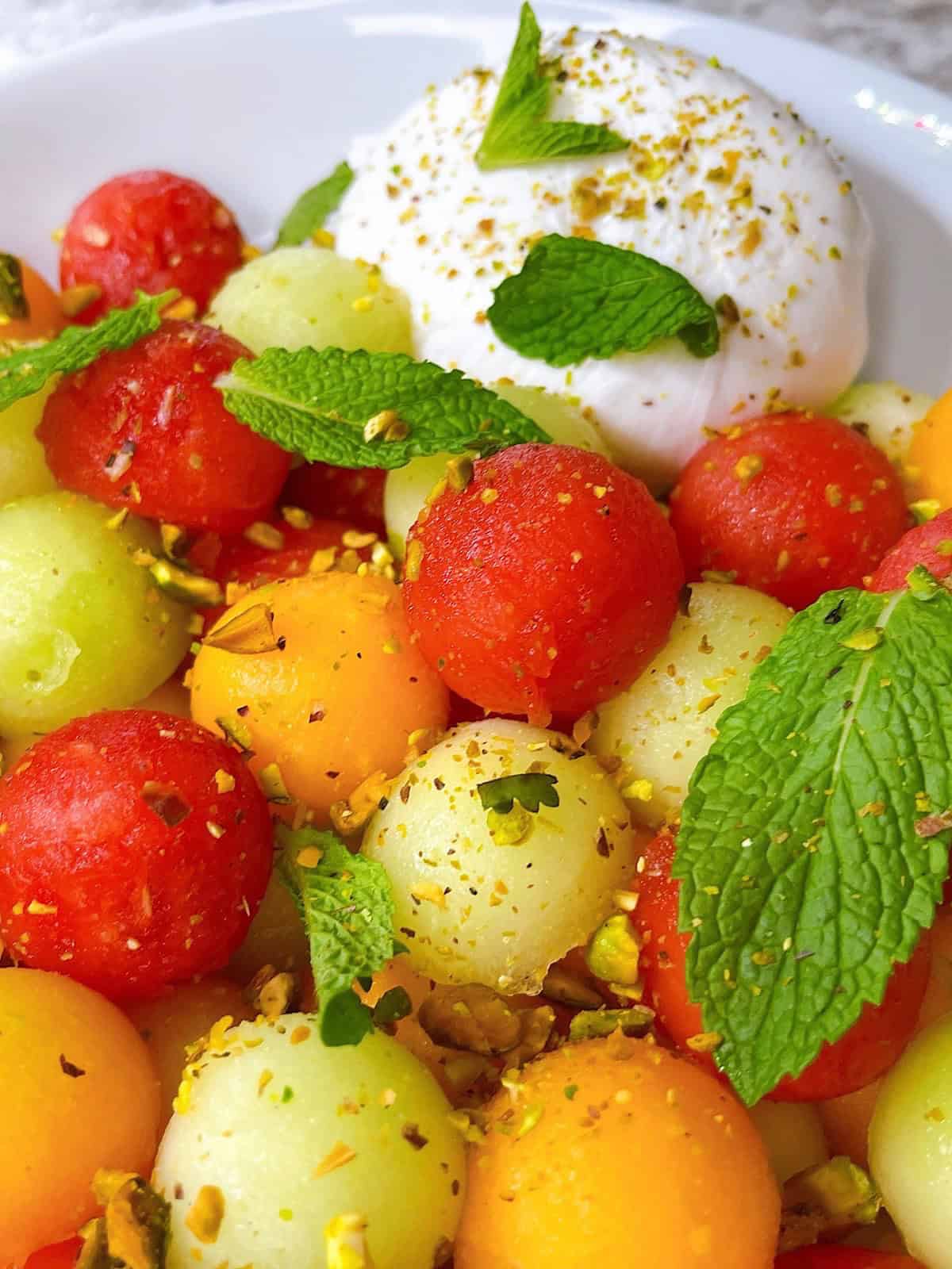 Melon salad with burrata pistachio and mint hero image close up dressed with toppings