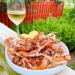 Sartin's signature deep fried bbq blue crabs copycat recipe feature image close up of fried crabs on platter on back deck next to a glass of white wine