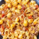 Southern goulash with beef and tomato feature image close up in black bowl