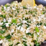 spanakorizo greek spinach rice with lemon and dill in the instant pot feature image close up in black bowl with lemon and feta crumbled.