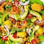 blackened shrimp and avocado salad with grilled corn in white bowl