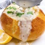 Clam chowder bread bowl close scooped with parsley and lemon feature image
